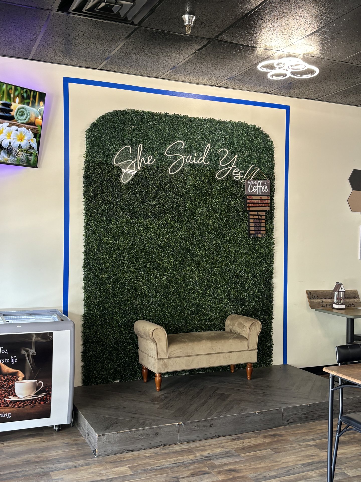 Cozy 'She Said Yes' seating nook with velvet bench and greenery wall at Panini Coffee House