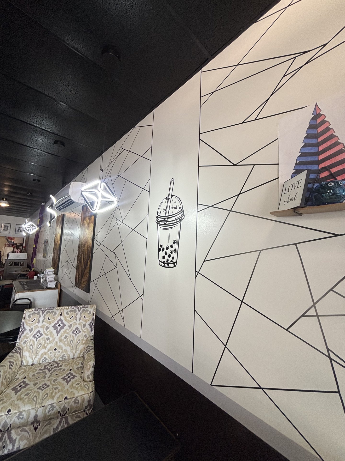 Geometric mural wall with boba tea artwork and lounge seating